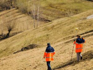 Surveyors performing a topographic survey on sloped terrain in Provo Utah